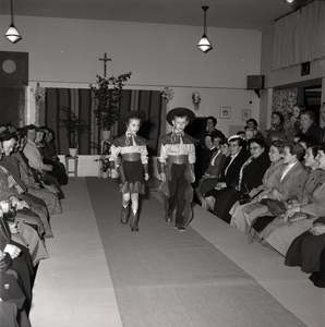 255029 Jongen en meisje tonen de toeschouwer hun cowboy-kleding op de catwalk, 1955