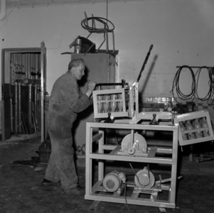 255100 Werknemer bedient de schudmachine met literflessen gepasteuriseerde melk. Geen verdere informatie bekend, 05-1955