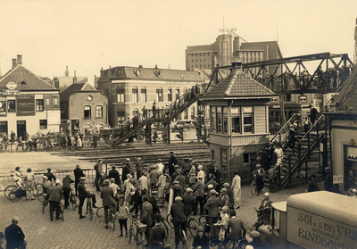 10049 Verkeersdrukte: fietsers en voetgangers bij de Woenselse overweg, met voetgangersbrug, 17-07-1928