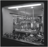 139929 Avondopname etalage van Brood en banketwinkel Jan Gruijthuijsen, Geldropseweg 58: het etaleren van bonbons, 11-1958