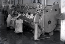 139957 Het vullen van een centrifuge met textiel door een medewerker van de wasinrichting, 1960