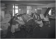 139959 Het strijken en vouwen van textiel door medewerksters van de strijkafdeling, 1960