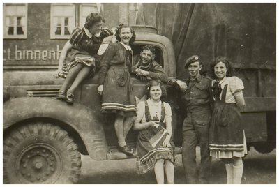 110043 Helmondse meisjes voor een Brits legervoertuig op de Markt voor meubelzaak 't Binnenhuis. Staande op de ...