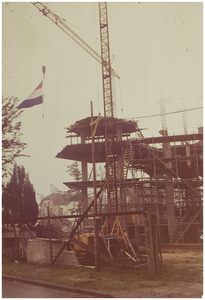 111969 Hijsen van de vlag bij het bereiken van de hoogste punt in de bouw van drie paalwoningen aan de Wilhelminalaan, ...