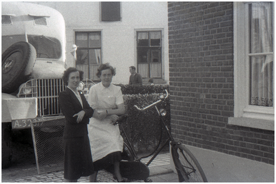 47594 Poseren voor woning met op achtergrond café Nouwen, Budel, 1960