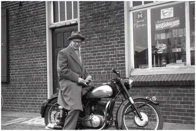 47625 Op motorfiets voor kruidenierswinkel P. Janssen in de Molenstraat, Budel, 1960