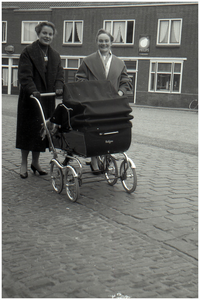 47635 Leun en Zus Schepens met kinderwagen (Hans Teeuwen) op de Markt in Budel. Op achtergrond bakkerij Rooijmans, 1967