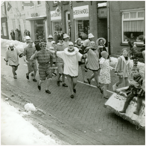 52457 Carnaval met op achtergrond boekhandel Neeskens en schoenhandel (Tasko) Mathijssen, Budel, ca 1960