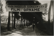 194505 Spandoek met de boodschap 'Geen onnoodige signalen s.v.p. film opname' t.b.v. een buitenopname van Philips NV, 1933