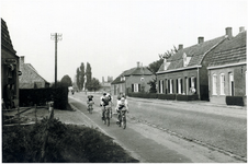 132290 Het wielerpeloton passeert de winkel van fotograaf Piet Waarma, Broek 147 (Dorpstraat), rechts vooraan woning ...