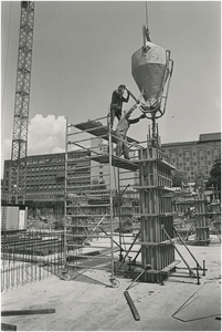 718 Bouwwerkzaamheden: het gieten van beton in een bekisting. Met op de achtergrond verzorgingshuis de Ravenshof en het ...