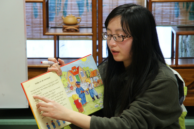 505540 Chinese vrouw toont een kinderboekje. op de achtergrond een kast met een theepotje, 2015