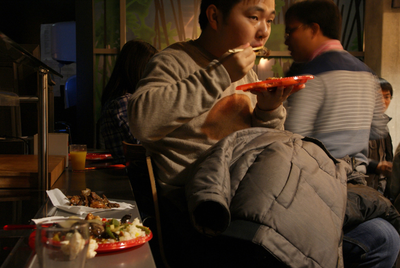 505542 Chineesbuffet bij Faculteit Scheikunde TU Eindhoven: chinese jongen eet met stokjes van een oranje bordje, 2015