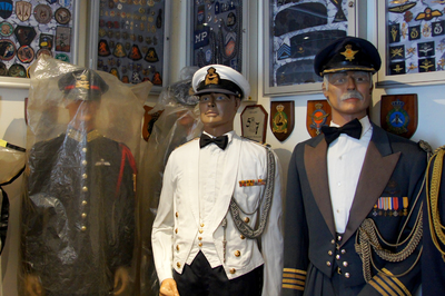 505258 Etalagepoppen gekleed in uniform, op de achtergrond vitrinekasten met emblemen , 2015