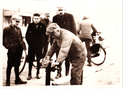 576400 Janus Wolters draait de kraan open. De man met de platte pet is veldwachter v.d. Grind, 1930