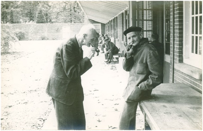 188674 Japie Mes (links) en onbekende cliënten, in de binnentuin van paviljoen CD, 1950 - 1960