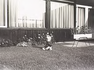 4531 Een kind op de grasmat voor een nieuw betrokken woning in de wijk Geestenberg, ca. 1972