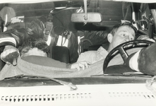 231637 Lotus slachtoffers liggen gewond in een auto ondersteund door een brandweerman, 19-04-1988