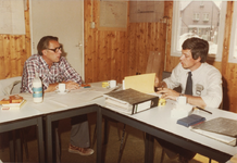 237006 Het houden van een bouwbespreking in de bouwkeet, met rechts gemeente- en bouwkundig opzichter Jos Verhoeven, ...