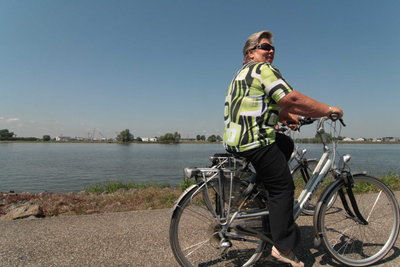403018 Een toerist fietsend over de dijk bij Werkendam langs de Merwede, Datum onbekend.