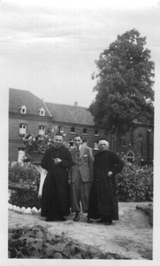 254136 Een familielid op bezoek bij twee broeders in de tuin van het klooster