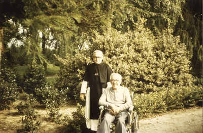 265404 Kruisheer Albert Sluis en Harrie Cuppen (in een rolstoel) in de kloostertuin van het klooster te St. Agatha