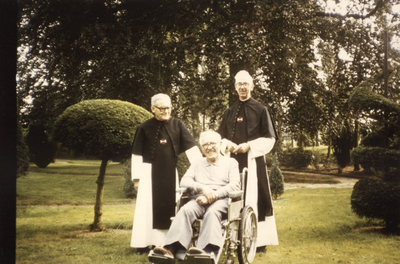 265405 Kruisheren Albert Sluis (links) en Ed Hollink (rechts) met Harrie Cuppen (in rolstoel) in de kloostertuin te St. ...