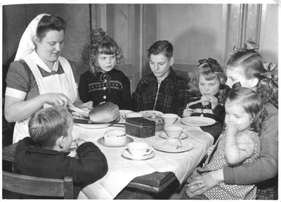 232097 Gezinsverzorgster van de Catechisten verzorgt een broodmaaltijd voor kinderen bij een gezin in West-Brabant