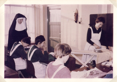 242085 Zuster Helena van de Dochters van O.L. Vrouw in haar naaiklas op school aan de Dobbelmannweg te Nijmegen
