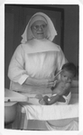 184133 Zuster Barthola op de babyafdeling van het klooster De Voorzienigheid te Paramaribo (Suriname)