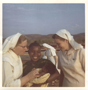 116181 De zusters Kunigunde en Johanna bewonderen een baby in Zuid-Tanzania