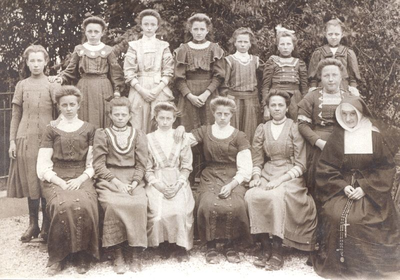 152384 Groepsfoto van zuster Christina met haar leerlingen van de R.K. Naaischool te Nieuw Vennep