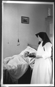 258006 Zuster Majella brengt een patiënte een lekker hapje in het pension te Kloosterburen