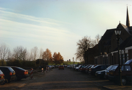  Parkeerplaatsen met rechts basisschool St. Antonius en de rk-kerk. Op de achtergrond de dijk.