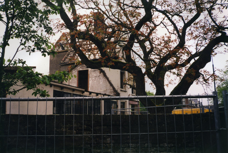  Van het witte huis op de hoek zijn de pannen van het dak verwijderd. Op de voorgrond de later gerooide notenboom.