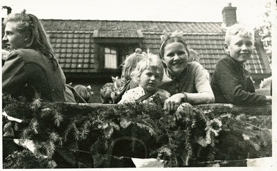 16827 - Op de foto is een wagen met dennentakken te zien. Het jongetje rechts is Gerrit Helmans en het meisje tweede ...