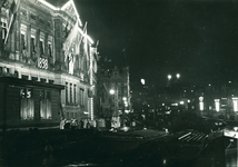 16953 - Nachtfoto van het Rokin met aan de linkerkant een gebouw met verlichting. Op het gebouw is 1898-1948 ...