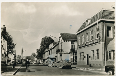1882 - Opname van een winkelstraat uit de jaren zestig van de vorige eeuw. Op de achtergrond de spitse toren van de ...