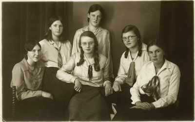 3639 - Zes jonge dames gekleed in rok en blouse. De dame links zittend is Clara van 't Ent; de dame rechts van haar is ...