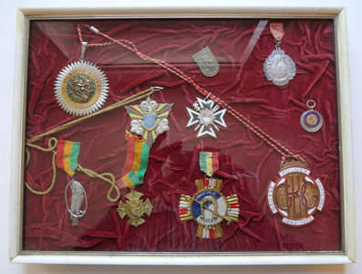 461 Onderscheidingen van Marotte Sittard e.a.Ingelijste verzameling onderscheidingen en medailles, opgespeld op rood ...