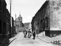 ehc_gp_014 Boer en boerin met koe onderweg in de Dorpstraat. Op de achtergrond de hoog gelegen kerk van Urmond 11-09-1935