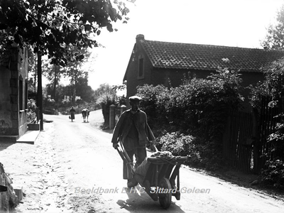 ehc_gp_015 Boer met kruiwagen en boerin met koe onderweg in een straat te Urmond 11-09-1935