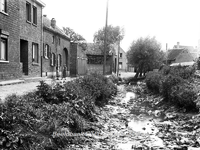 ehc_gp_073 Beekstraat te Nieuwstadt met 2 pratende huisvrouwen en kleuter. De Geleenbeek staat bijna droog. 18-06-1937