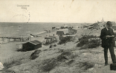 PB4963 Duin en strand met toegang tot steiger voor boot. Een man staat iets te lezen op het duin, 1912