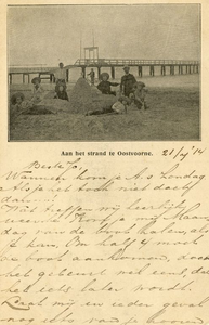 PB5465 Aan het strand te Oostvoorne. Kinderen spelen in het zand, het steiger op de achtergrond, ca. 1914