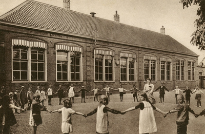 PB9617 De Openbare Lagere School van Vierpolders. De kinderen staan in een kring op het schoolplein met in het midden ...