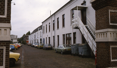 DIA20134 Kijkje door de voormalige toegangspoort van de marinewerf, met kijkje op het Grootmagazijn; ca. 1983