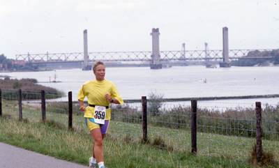 DIA42659 Hardloopster langs de Oude Maas. Op de achtergrond de Spijkenisserbrug; Augustus 1990