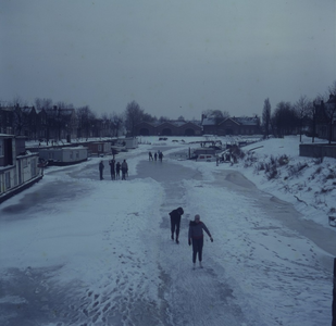 DIA_GF_1077 Het Kostverloren is dichtgevroren, schaatsers vermaken zich op het ijs; winter 1963