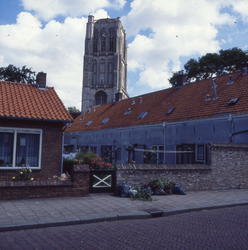 DIA_GF_1561 Een straatje in Den Briel, met de toren van de St. Catharijnekerk op de achtergrond; 5 augustus 1986